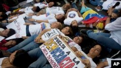 FILE - Opposition supporters lie on the ground during a demonstration outside of the Organization of American States, OAS, office building, in Caracas, Venezuela, June 23, 2016.