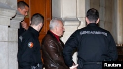 FILE - Ilich Ramirez Sanchez, known as "Carlos the Jackal," is surrounded by French gendarmes as he leaves the Paris courthouse, March 3, 2014. 