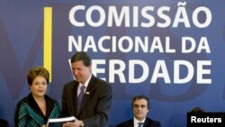 Presiden Brazil Dilma Rousseff (kiri) menerima laporan dari Pedro Dallari, anggota Komisi Kebenaran, di Brasilia (10/12). (Reuters/Joedson Alves)