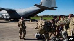 This Oct. 29, 2018 photo provided by the U.S. Air Force shows deployers from Headquarters Company, 89th Military Police Brigade, Task Force Griffin getting ready to board a C-130J Super Hercules from Little Rock, Arkansas, at Fort Knox, Kentucky.