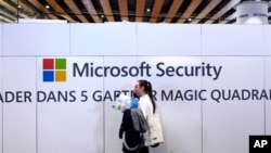 FILE - A woman walks in front of the Microsoft stand during the Cybersecurity Conference in Lille, northern France, January 29, 2020. 
