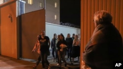 Women walk through a gate after being released from a detention center where protesters were detained during a mass rally following presidential election in Minsk, Belarus, Aug. 14, 2020. 