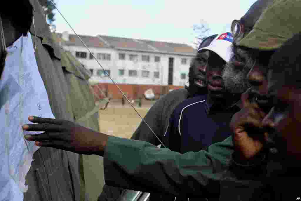 Voters look at posted results outside a polling station in Harare, August 1, 2013.