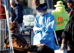 FILE - A medical student from Touro University Nevada talks with a man in a temporary parking lot shelter at Cashman Center, in Las Vegas, Nevada, March 30, 2020.