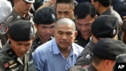Thai policemen escort the fortune teller, Suriyan Sutjritpolwongse, center, better known by the nickname "Mor Yong," as he arrives at military court in Bangkok, Thailand, Oct. 21, 2015. 