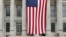 Two people sit on the steps of Brooklyn's Borough Hall where a huge American flag is displayed, July 3, 2014.