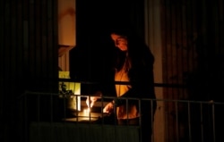 A woman lights a candle on her balcony as faithful across Italy say a prayer for people suffering from coronavirus disease (COVID-19), in Rome, March 19, 2020.