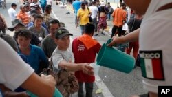 Central American migrants eat lunch, courtesy of Mexican officials, on the border bridge between Mexico and Guatemala, as they wait for their humanitarian visas from Mexican migration officials to be processed.