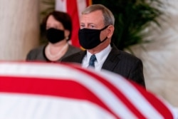 Chief Justice of the US Supreme Court, John Roberts (R) and Justice Elena Kagan (L), watch as the flag-draped casket of Justice Ruth Bader Ginsburg arrives at the Supreme Court in Washington, DC, on Sept. 23, 2020.