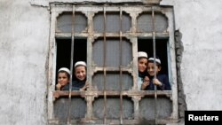 Afghan students from a religious school look on from a window of their school in Kabul, Afghanistan, Oct. 5, 2016.