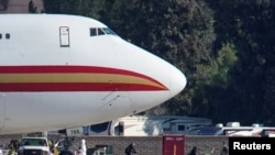FILE - Women and children walk past personnel after arriving on an aircraft chartered by the U.S. to evacuate Americans from the Chinese city of Wuhan, at March Air Reserve Base in Riverside County, California, Jan. 29, 2020. 