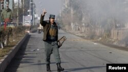Seorang polisi Afghanistan memberikan komentar saat melihat asap akibat serangan di dekat konsulat Pakistan di Jalalabad, Afghanistan (13/1).