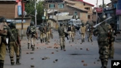 FILE - Indian government forces patrol a street dotted with rocks and bricks used during a protest in Srinagar, Indian-controlled Kashmir, Sept. 7, 2016.