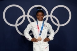 Simone Biles, of the United States, poses wearing her bronze medal from balance beam competition during artistic gymnastics at the 2020 Summer Olympics, Tuesday, Aug. 3, 2021, in Tokyo, Japan. (AP Photo/Natacha Pisarenko)