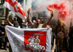 People light flares and wave Belarusian flags in front of the Belarusian Embassy in Kyiv, Ukraine, Aug. 14, 2020.
