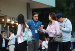 An electoral staff member helps a voter at a polling station during district council local elections in Hong Kong, Nov. 24, 2019.