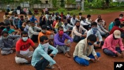Migrant workers from Bihar state, wearing masks as a precaution against the coronavirus, wait for buses to catch a homebound train in Kochi, southern Kerala state, India, June 12, 2020.