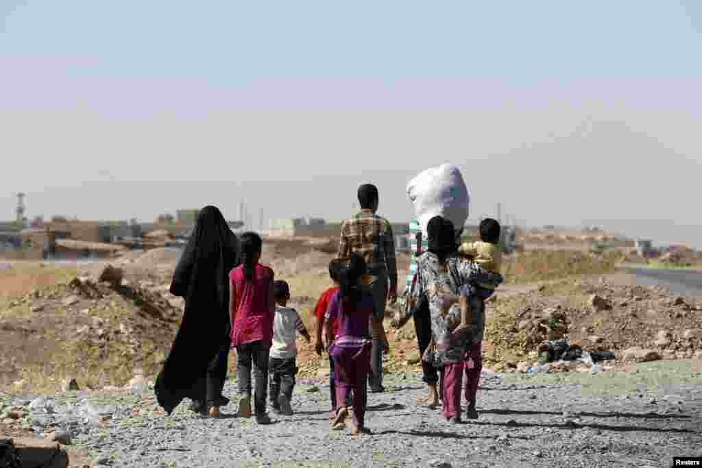 A displaced family from the minority Yazidi sect walks towards the entrance of Mosul, Aug. 21, 2014.