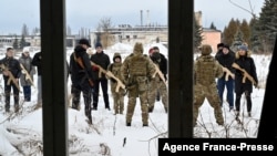 A military instructor teaches civilians holding wooden replicas of Kalashnikov rifles, during a training session at an abandoned factory in the Ukrainian capital of Kyiv on Jan. 30, 2022.