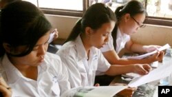 FILE - Students read first-ever Cambodian-authored Khmer Rouge history textbook during its delivery to high school students in Phnom Penh, Cambodia, Oct. 10, 2009.