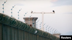FILE - Security cameras are seen above the perimeter fence of what Beijing calls a vocational training center, in Dabancheng, in China's Xinjiang region, China, Sept. 4, 2018.