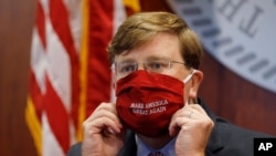 Mississippi Gov. Tate Reeves adjusts his "Make America Great Again," face mask upon concluding his press briefing with members of the state's COVID-19 response team, to discuss the ongoing strategy to reduce and limit transmission, July 20, 2020, 