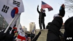 ইউন-পন্থী সমর্থকরা, পিছনে, সোওল ওয়েস্টার্ন ডিস্ট্রিক্ট কোর্টের প্রাঙ্গণে প্রবেশের চেষ্টা করার সময় পুলিশ প্রহরায় দাঁড়িয়ে আছে, ১৮ জানুয়ারী, ২০২৫। আদালত দক্ষিণ কোরিয়ার অভিশংসিত প্রেসিডেন্ট ইউন সুক ইওলের আটকের মেয়াদ বাড়ানো হবে কিনা তা নিয়ে বিবেচনা করছে। 