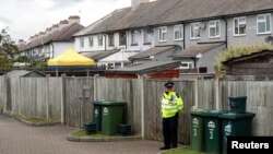 Seorang polisi siaga di sebuah rumah terkait dengan penangkapan tersangka dalam pemboman London di kota Sunbury-on-Thames, Surrey, Inggris, Minggu (17/9). 