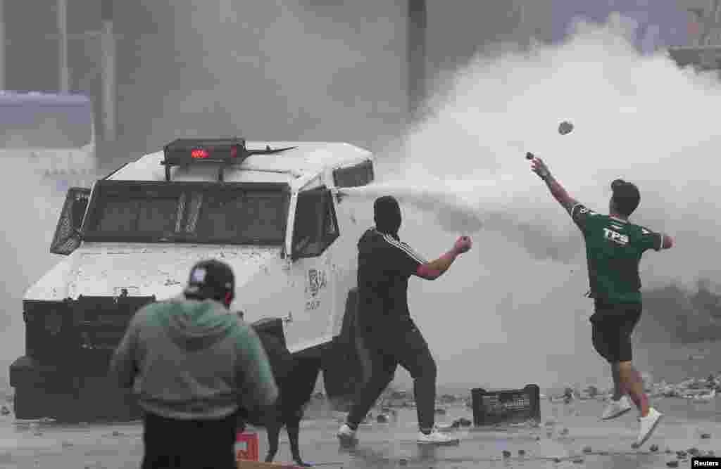 Demonstrators throw rocks in clashes with riot police during a protest by fishermen against the government, where they demand the approval a new fishing law in the congress, in Valparaiso, Chile.