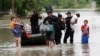 FILE - Residents walk through floodwaters after being evacuated from their flooded apartment complex, in Houston.