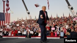 Presiden AS Donald Trump membuang maskernya ke arah pendukungnya dalam kampanye di Sanford, Florida. 