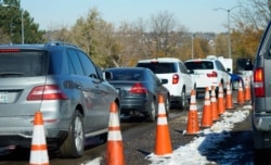 A long line of motorists wait at a drive-in COVID-19 testing site in Federal Heights, Colo., Oct. 27, 2020.