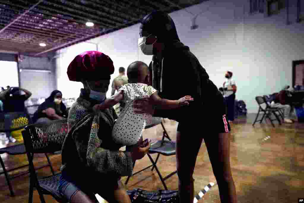 Alaira Brown, right, takes her niece Delilah Francis, 6 months, from Ledonna Brown, as they wait to board buses to evacuate Lake Charles, La., Aug. 26, 2020, ahead of Hurricane Laura. 