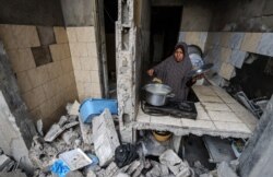 A Palestinian woman who has returned to her neighborhood cooks a meal in what remains of her home, hit by Israeli bombardment in Gaza City, after a cease-fire brokered by Egypt between Israel and Hamas, May 21, 2021.