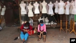 Perempuan duduk di depan manekin di pasar tekstil yang tutup akibat pandemi virus corona, di Jakarta, 30 April 2020. (Foto: AP)