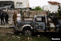 People gather at the scene where a projectile fell next to a destroyed vehicle, after projectiles crossed over to Israel from Lebanon, amid ongoing hostilities between Hezbollah and Israel, in Petah Tikva, Israel, Nov. 24, 2024.