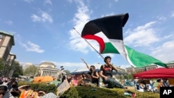 Seorang demonstran mengibarkan bendera Palestina dalam aksi protes di area kampus Columbia University di New York, pada 29 April 2024. (Foto: AP/Ted Shaffrey)