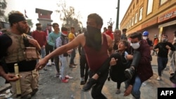 Iraqi anti-government protesters carry away an injured comrade amid clashes with security forces by Baghdad's Rasheed Street near Ahrar Bridge, Nov. 29, 2019. 