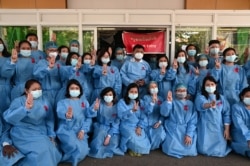 FILE - Medical workers wearing red ribbons pose during a protest against the coup that ousted elected leader Aung San Suu Kyi, in Yangon General Hospital in Yangon, Myanmar, Feb. 3, 2021.