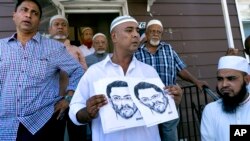 Members of the Al-Furqan Jame Mosque in Queens, New York, display a police sketch of a man suspected of shooting two clerics Saturday. Oscar Morel, 35, has been charged in the crime.