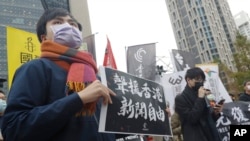 FILE - A supporter holds a sign reading "Support Press Freedom in Hong Kong" to protest outside of the Bank of China in Taipei, Dec. 30, 2021.