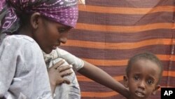 A refugee woman from southern Somalia attends to her malnourished child in their makeshift shelter in a refugee camp in Mogadishu, Somalia, Aug. 6, 2011