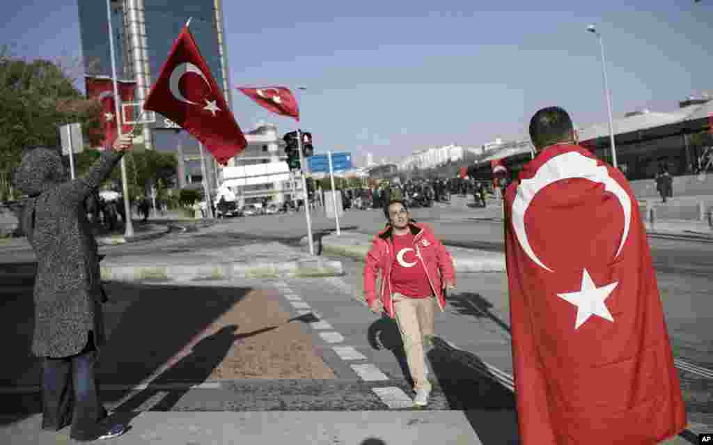 People walk past the Besiktas football club stadium Vodafone Arena in Istanbul, Dec. 11, 2016, following the late Saturday explosion.