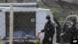 Police stand near a coroner's car containing bodies found in a mass grave in Durango, April 20, 2011