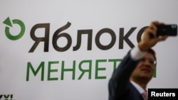 A participant takes a selfie in front of a banner during a congress of the political party Yabloko in Moscow, Russia, April 3, 2021. A banner reads: "Yabloko is changing." 