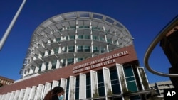 FILE - A woman wearing a mask walks past Zuckerberg San Francisco General Hospital and Trauma Center in San Francisco, Dec. 14, 2020.