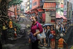A woman wears a face mask to protect herself from COVID-19 as she walks past a painting in Hong Kong, April 25, 2020.
