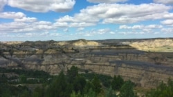 The sun and clouds create a shifting color palette on the badlands landscape