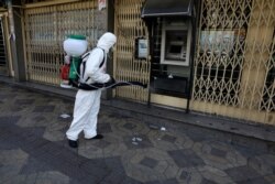 A firefighter disinfects an ATM machine to help prevent the spread of the new coronavirus in Tehran, Iran, March 5, 2020.