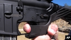 Shooting instructor Frankie McRae illustrates the grip on an AR-15 rifle fitted with a "bump stock" at his 37 PSR Gun Club in Bunnlevel, N.C., Oct. 4, 2017. The stock uses the recoil of the semiautomatic rifle to let the finger "bump" the trigger, making it different from a fully automatic machine gun, a type that is illegal for most civilians to own.